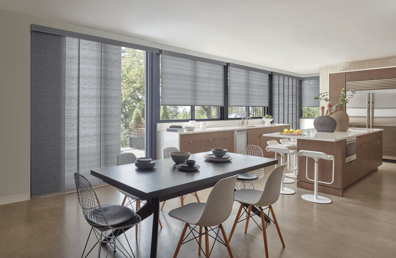 Open concept dining room and kitchen featuring large sliding glass doors with panel shades.